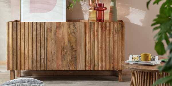 Habitat wooden sideboard with homeware accessories against pink wall.